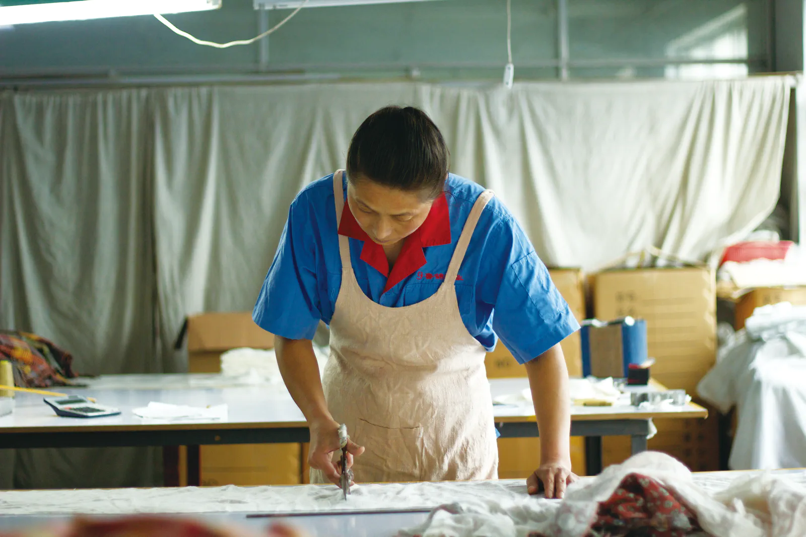 手作業で一枚ずつ和紡布を断裁する職人の様子｜益久染織研究所